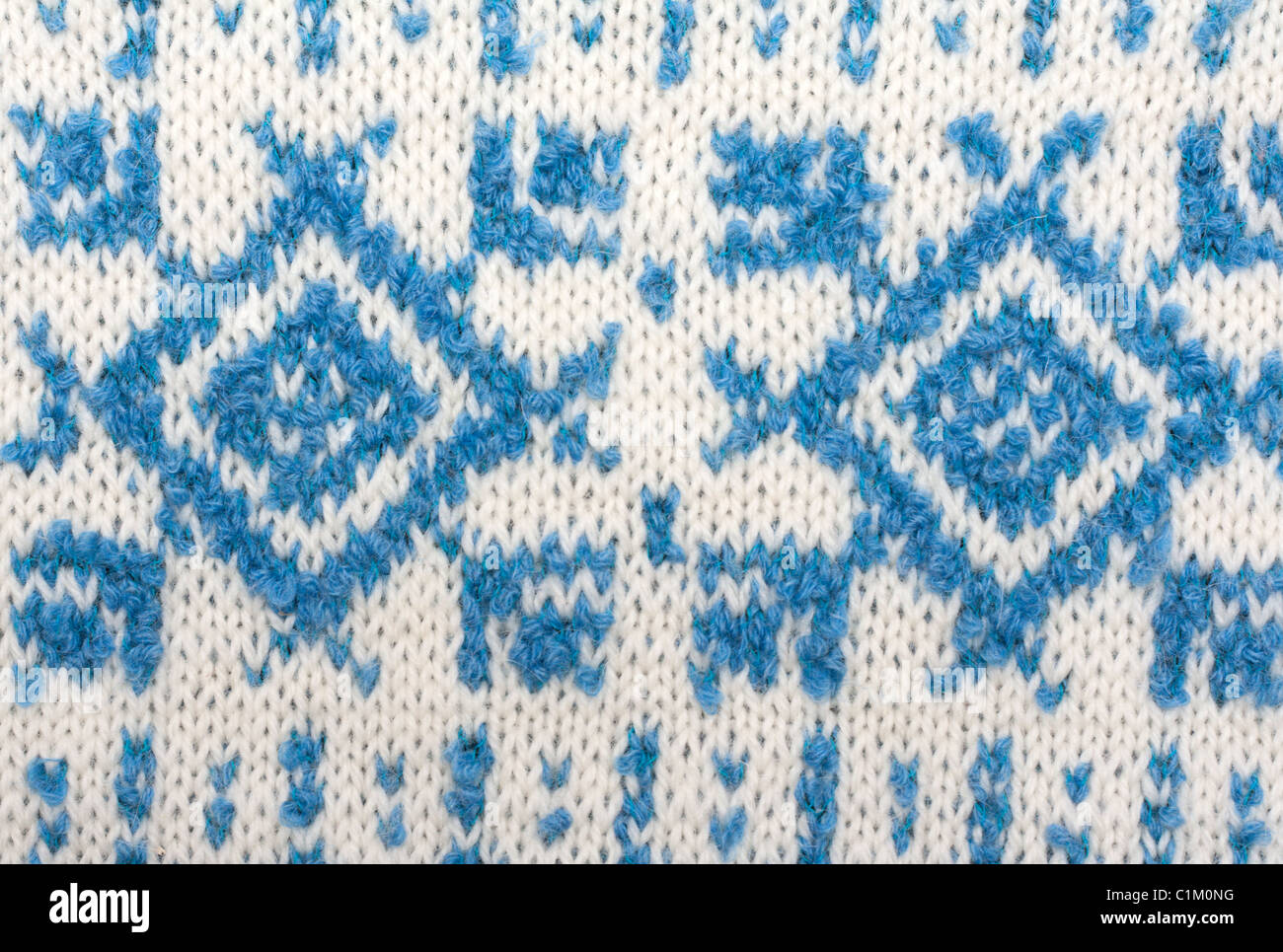 Knitted background with pattern in the manner of snowflakes, sweater Stock Photo