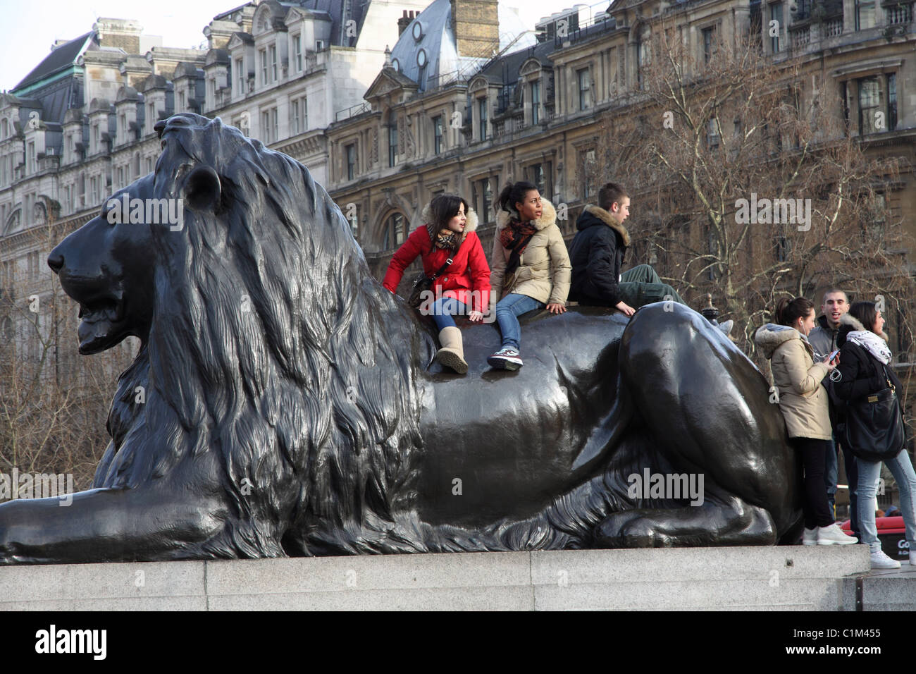 Young people on lion statue in London'sTrafalgar Square Stock Photo