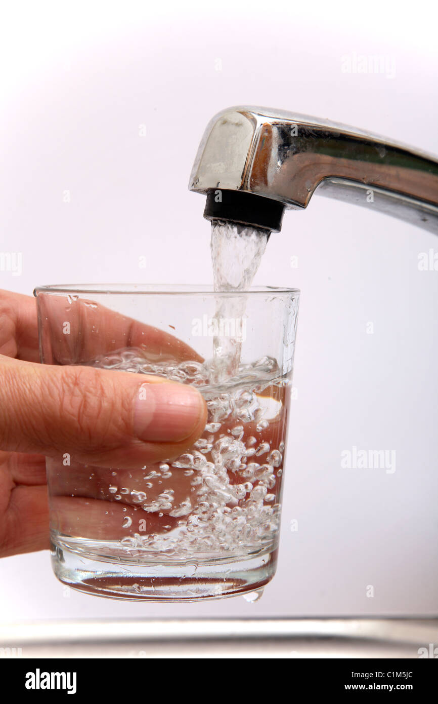 Man filling a glass with water from a kitchen tap. Stock Photo
