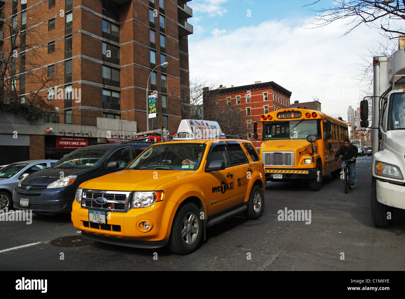 Yellow cab with Yellow school bus to rear, Manhattan, New York, United States of America. Stock Photo
