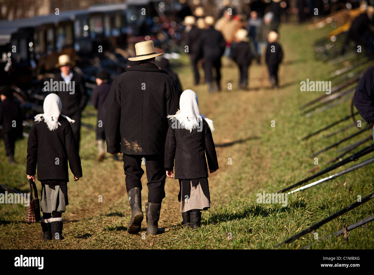 Amish man holds hands with his daughters at the annual Mud Sale and auction Gordonville, PA. Stock Photo
