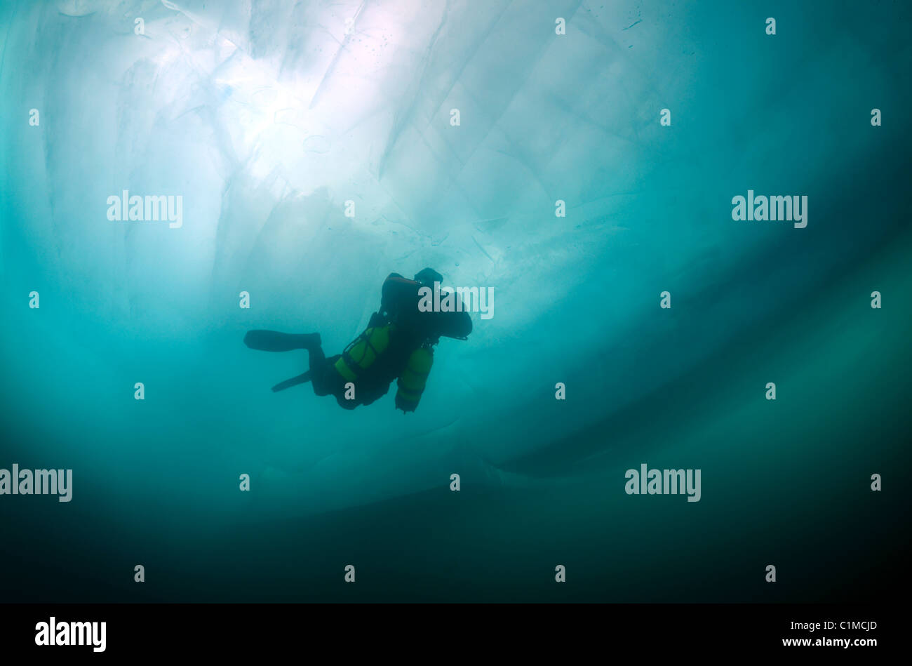 Scuba diver in sidemount swim under ice. icediving, in lake Baikal
