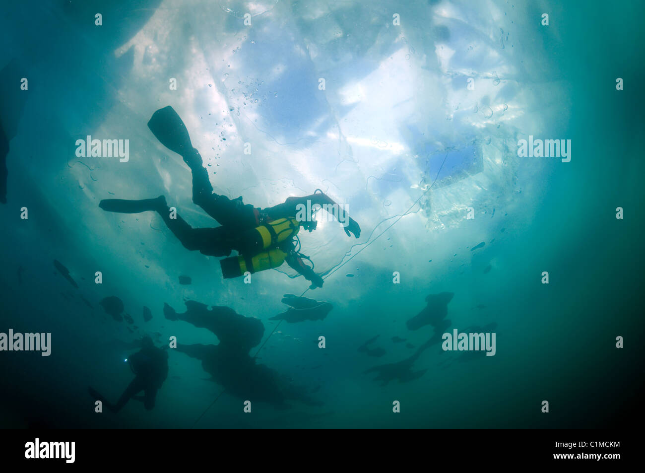 Scuba diver in sidemount swim under ice. icediving, in lake Baikal