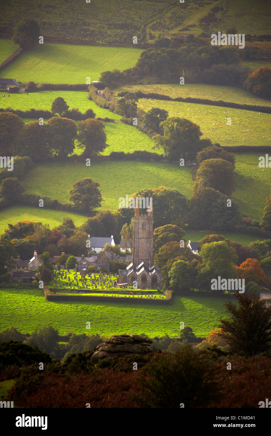 Sunlight spotlights the small village church at Widecombe in the Moor on Dartmoor Devon UK Stock Photo