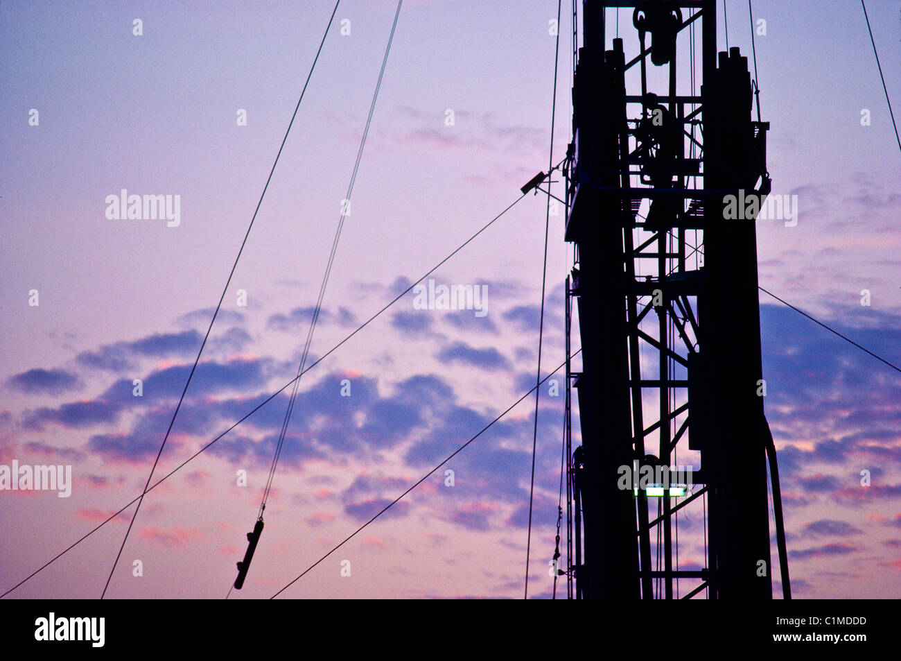 Oil rig derrick with worker working drill pipe at top of derrick at ...
