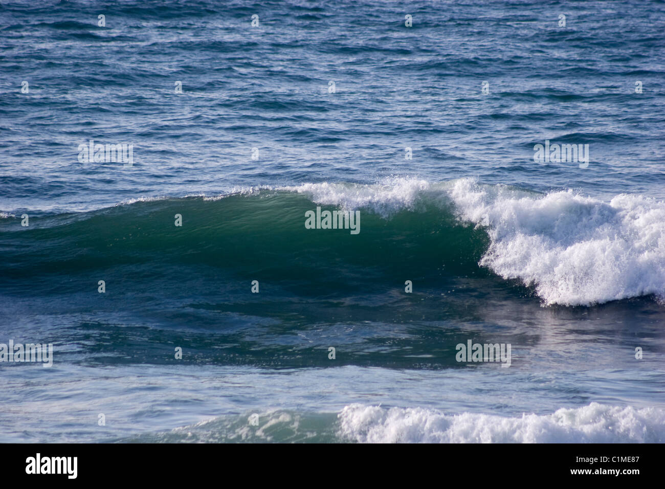 sea water wave break surf curl crash wake parallel beach sunny day reflection seaside ripple swell blue green white foam crest Stock Photo