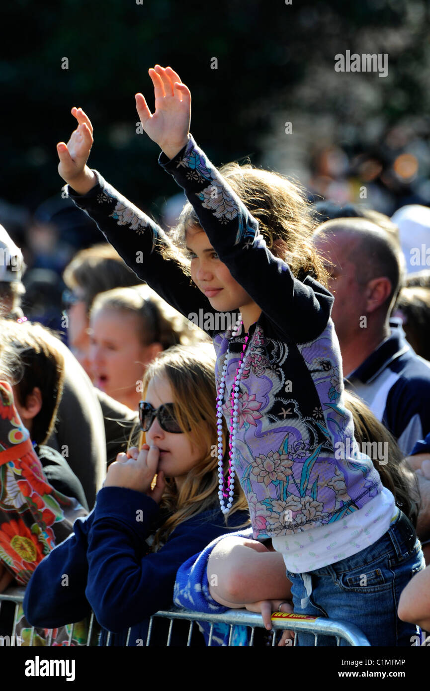 Young girl raises hands and arms in crowd during Gasparilla Pirate Festival Parade Tampa Florida Stock Photo
