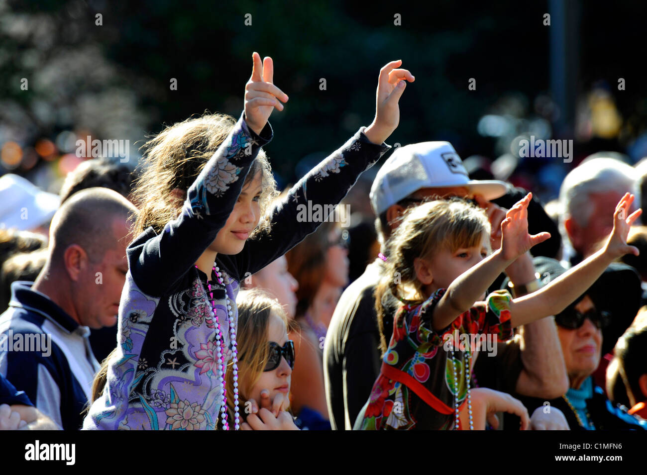 Young girl raises hands and arms in crowd during Gasparilla Pirate Festival Parade Tampa Florida Stock Photo