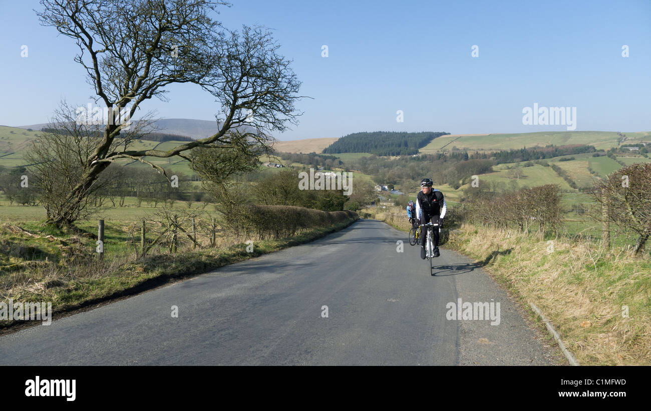 Cycling up a steep hill in early spring, Lancashire Stock Photo