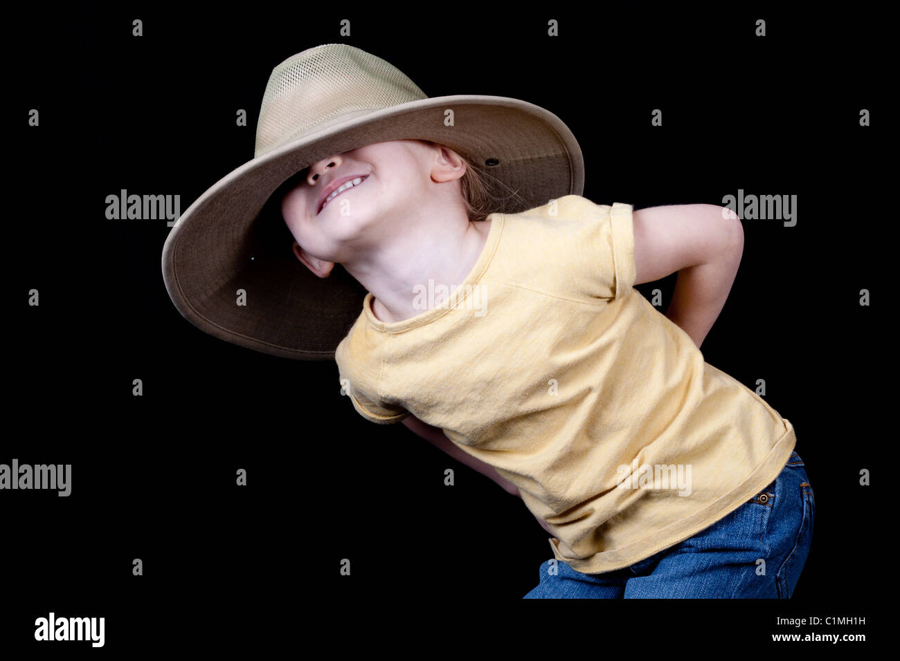 A cute girl with an over-sized hat on her head. It is pulled over her eyes. Stock Photo