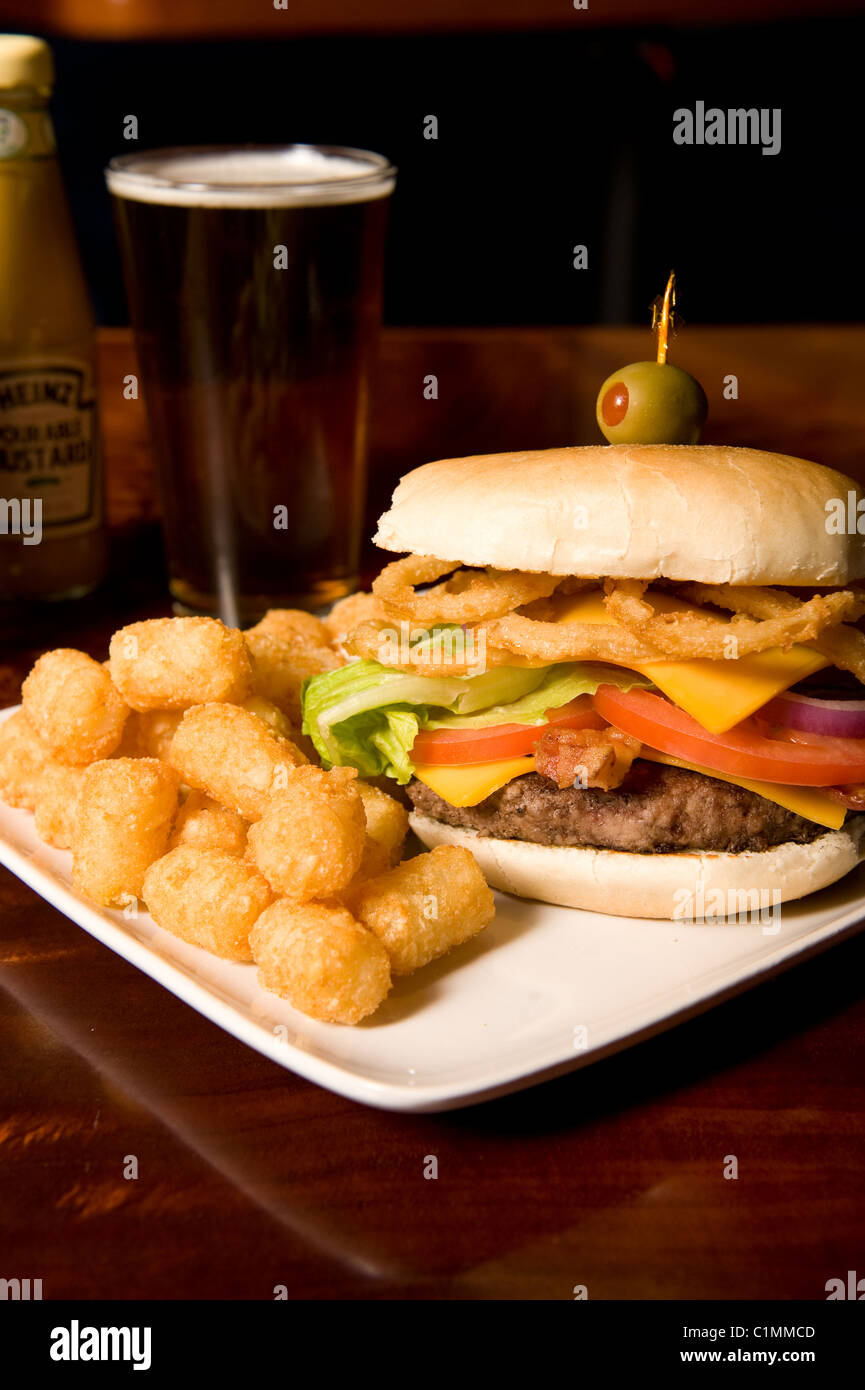 Deluxe hamburger, tater tots, and beer served at a restaurant Stock Photo