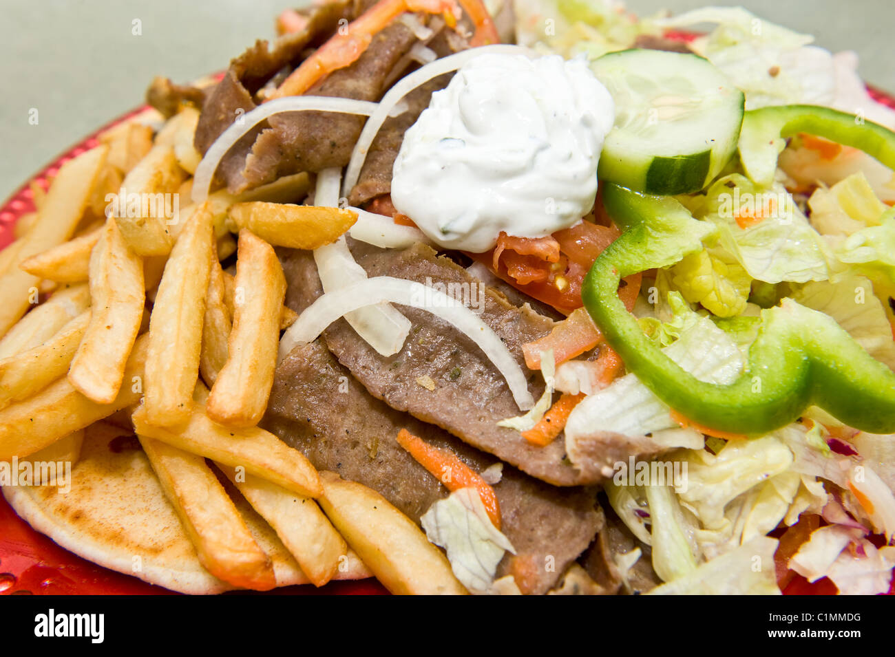 Large serving of Greek gyro sandwich served with French fries, vegetables, and condiments Stock Photo