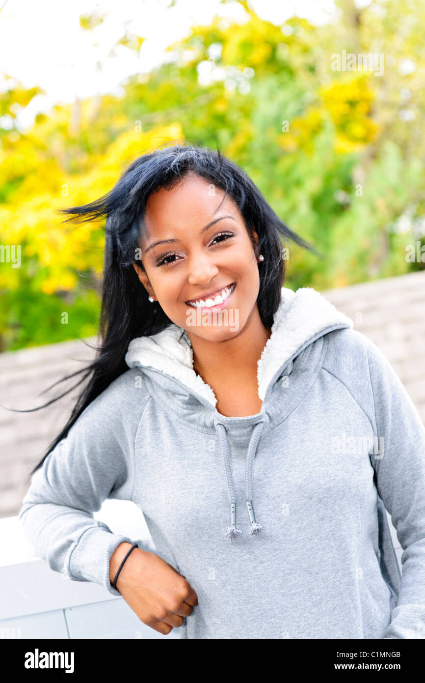 Smiling young black woman outside in casual hoodie on windy day Stock