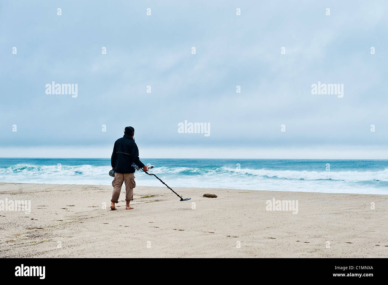 Man searching the beach with a metal detector. Stock Photo