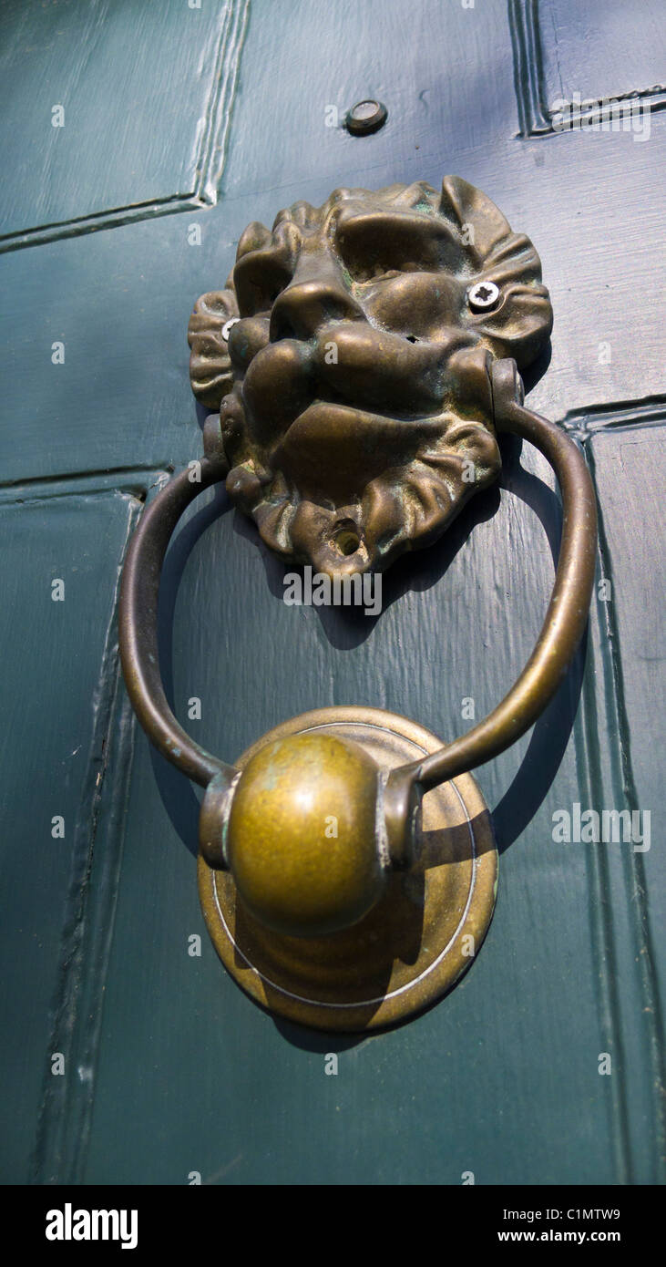 Brass lion's head door knocker on a green painted door. Stock Photo