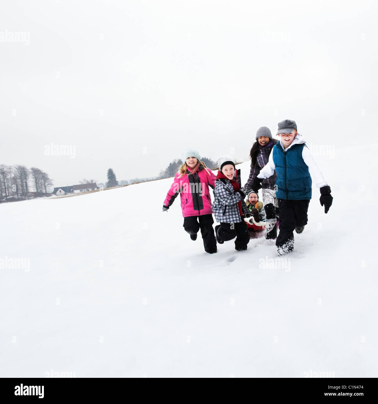 Children tobogganing on snow slope Stock Photo