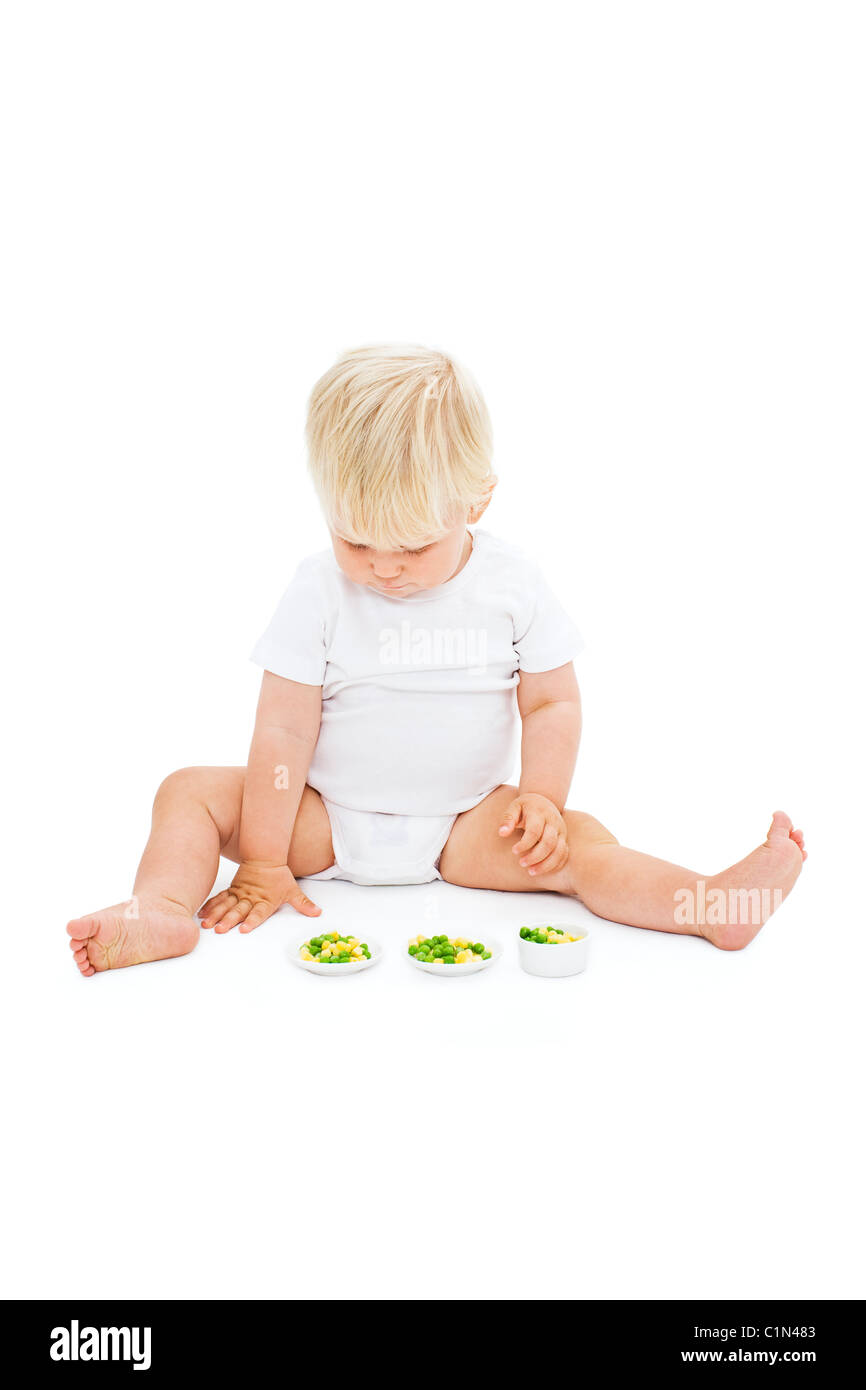 Studio shot of baby boy looking at peas Stock Photo