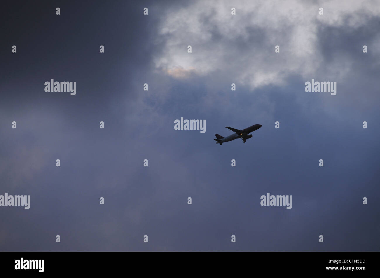 Plane flying at a cloudy sky Stock Photo