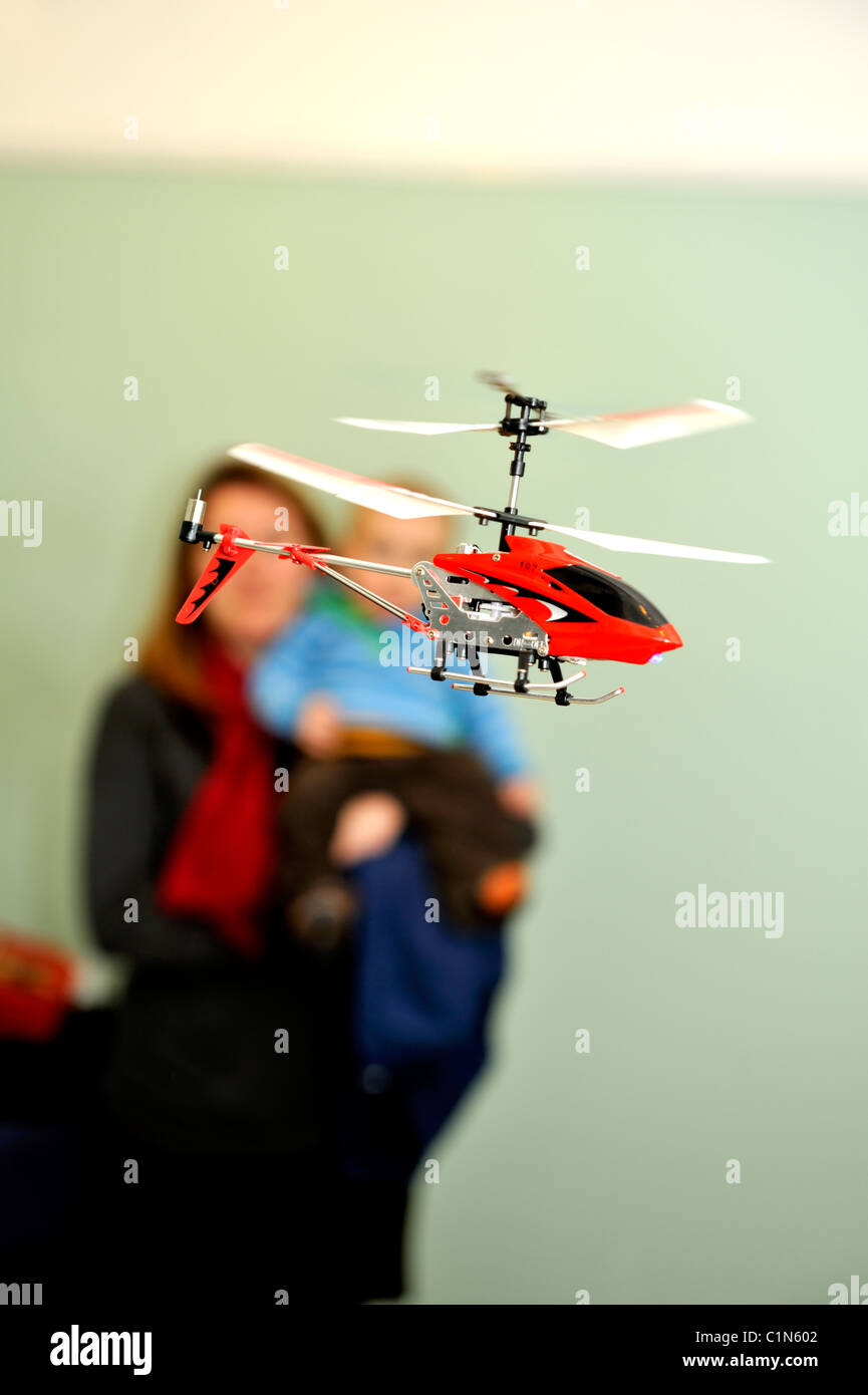 Remote controlled toy helicopter flying indoors, mother and child