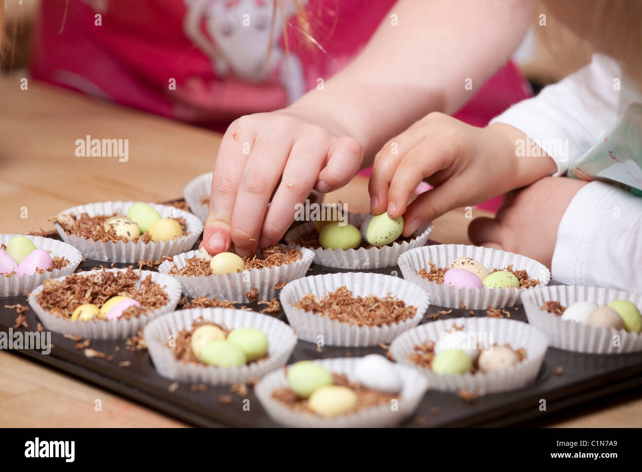 Children making Easter nest cakes with shredded wheat and mini
