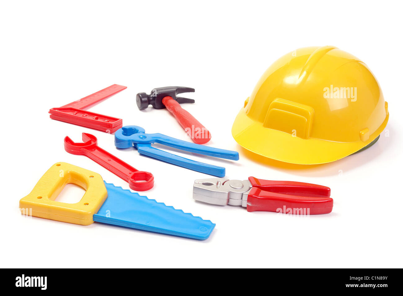 Assorted plastic toy tools and yellow helmet over white background Stock Photo
