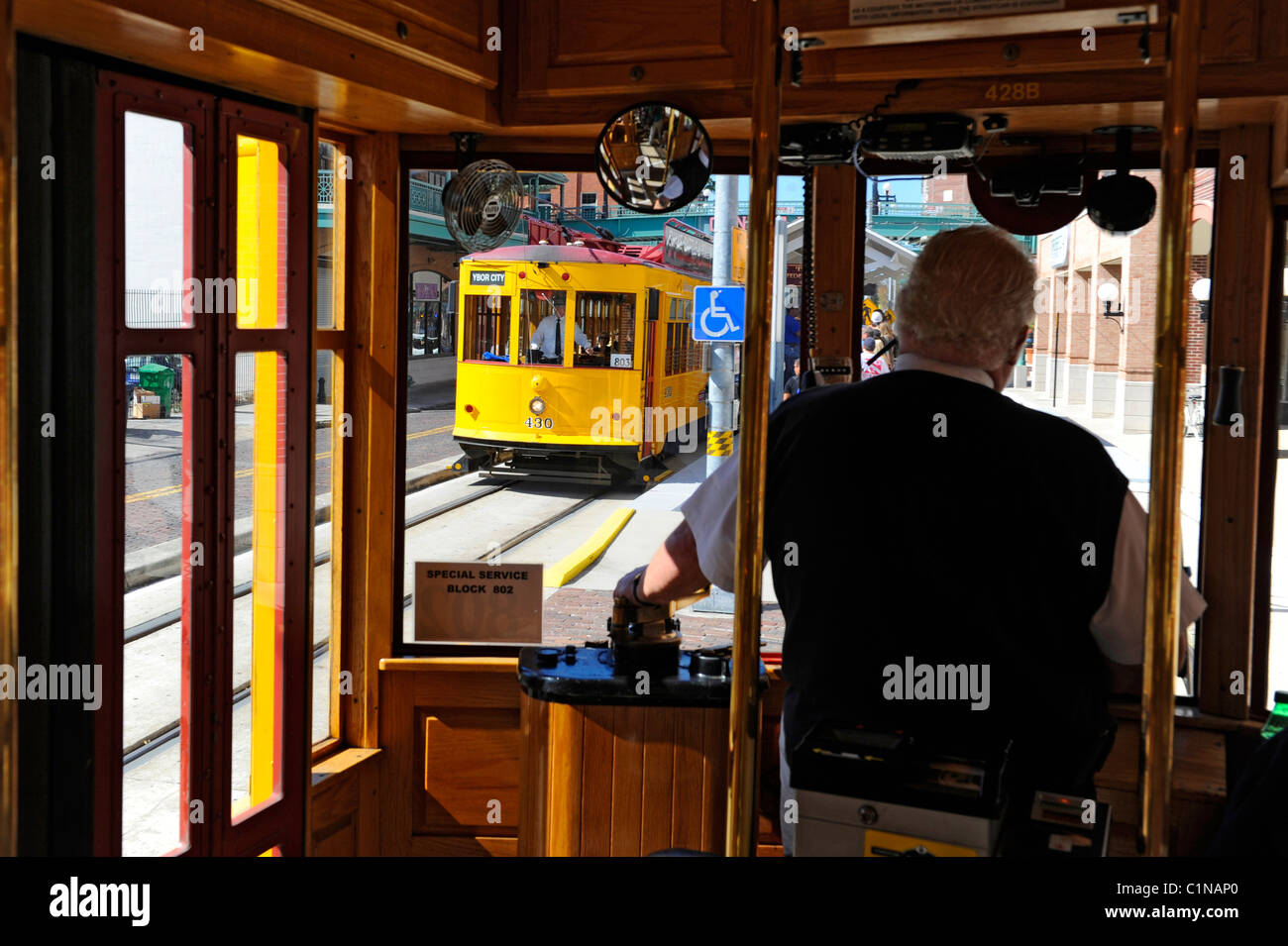 Conductor runs yellow historic trolley on track in Ybor City Tampa Florida Stock Photo