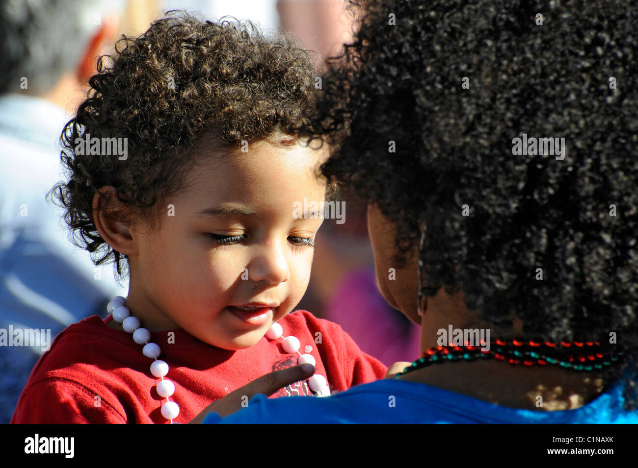 Young African American child with mother at annual Tampa Florida Gasparilla Pirate Festival Parade Stock Photo