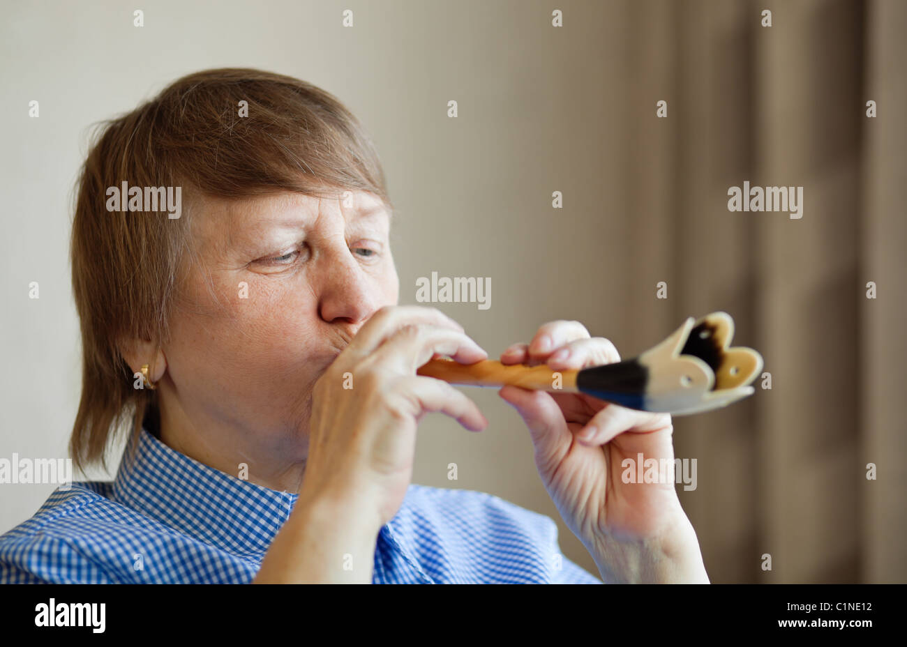 Elderly woman playing a wind instrument at home Stock Photo Alamy