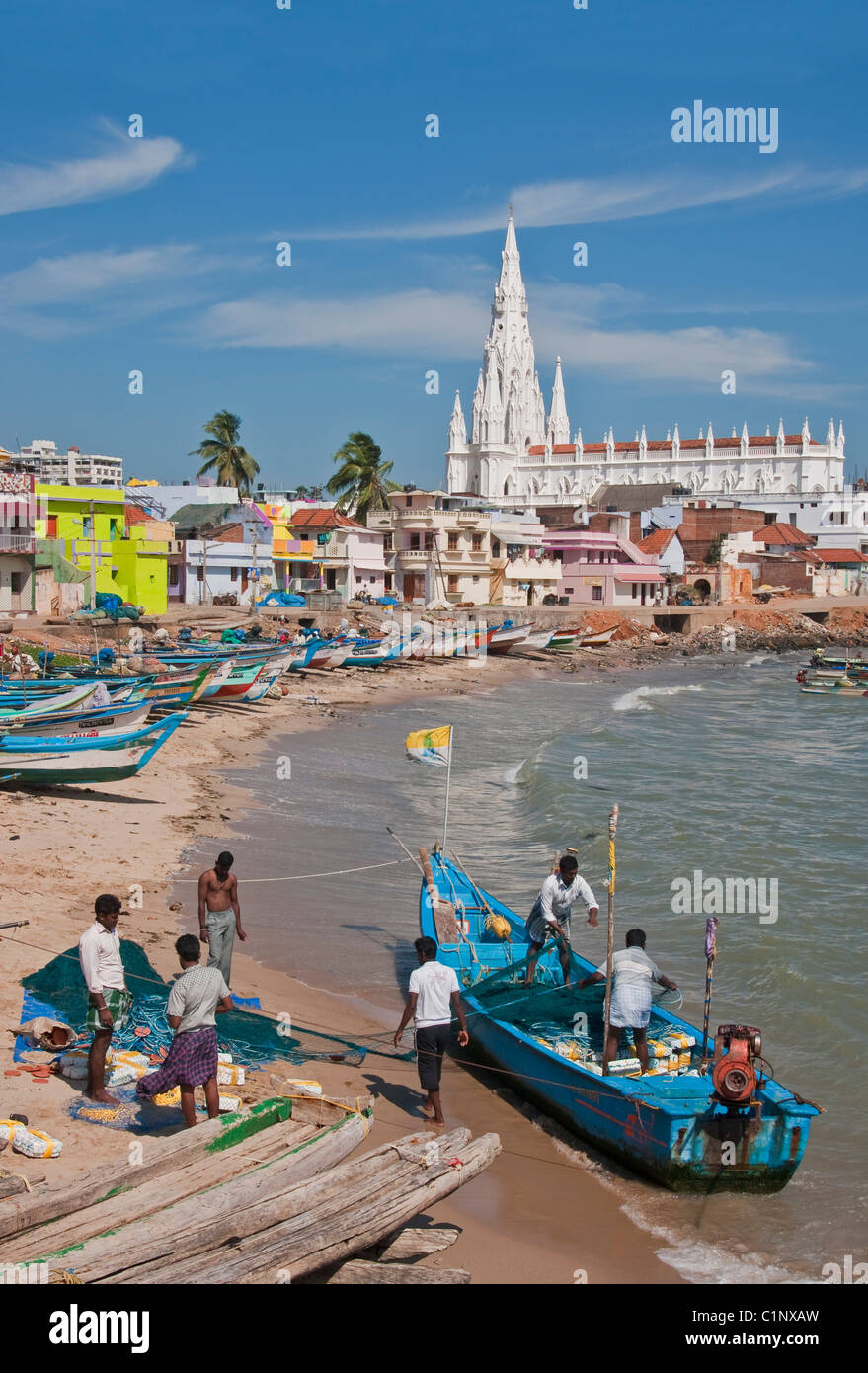 Fishermen on Kanyakumari Beach waterfront preparing nets with Our Lady of Ransom Church in background. Stock Photo
