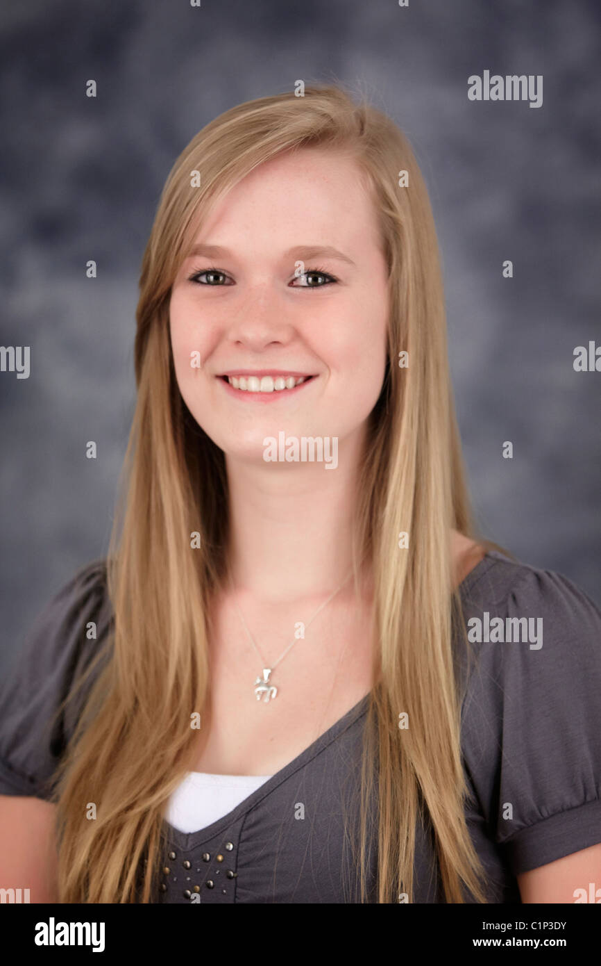 A Young Teenage Girl With Blonde Hair In Front Of Gray Background