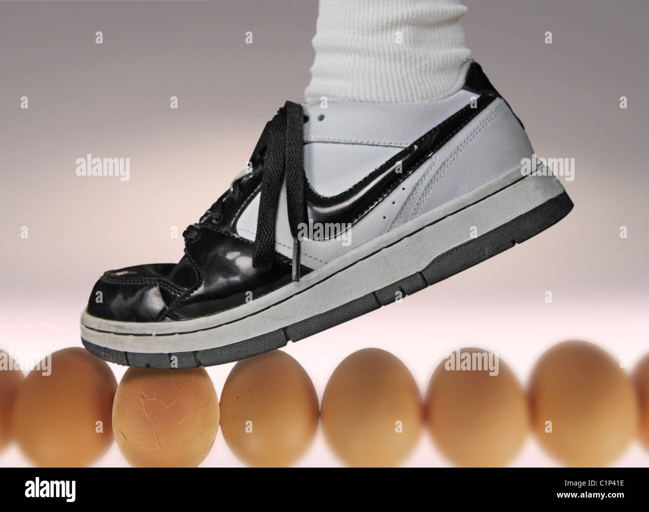 foot wearing running shoe walking on eggshells, one egg cracked! Stock