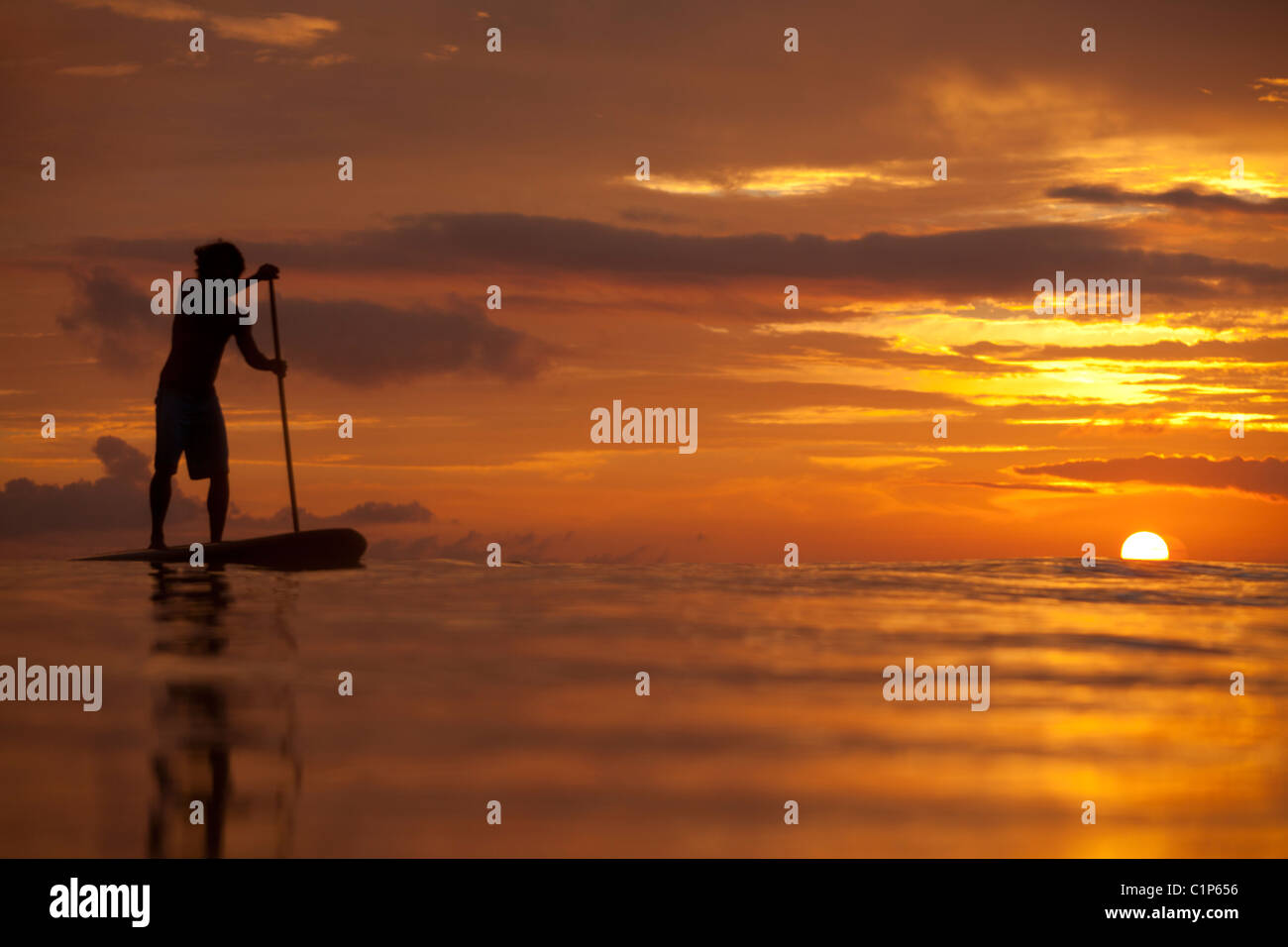 A stand-up paddler paddles in Kailua Bay  during a gorgeous sunrise on the island of Oahu, Hawaii. Stock Photo