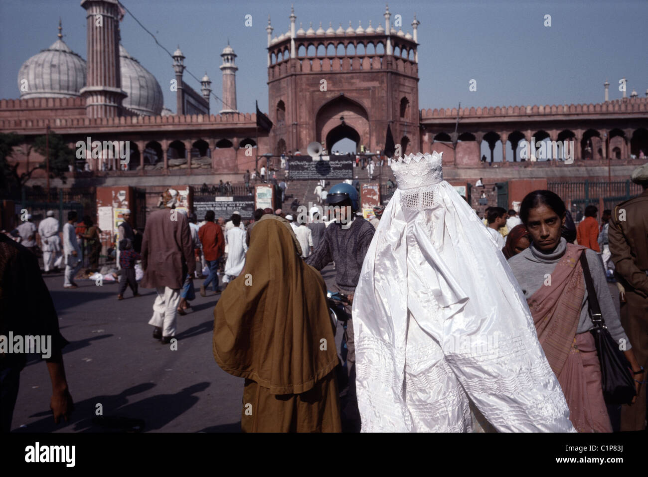 A Muslim woman in a burqa walks near the Jama Masjid in Old Delhi. The Mughal Emperor Shah Jahan constructed the mosque in 1656. Stock Photo