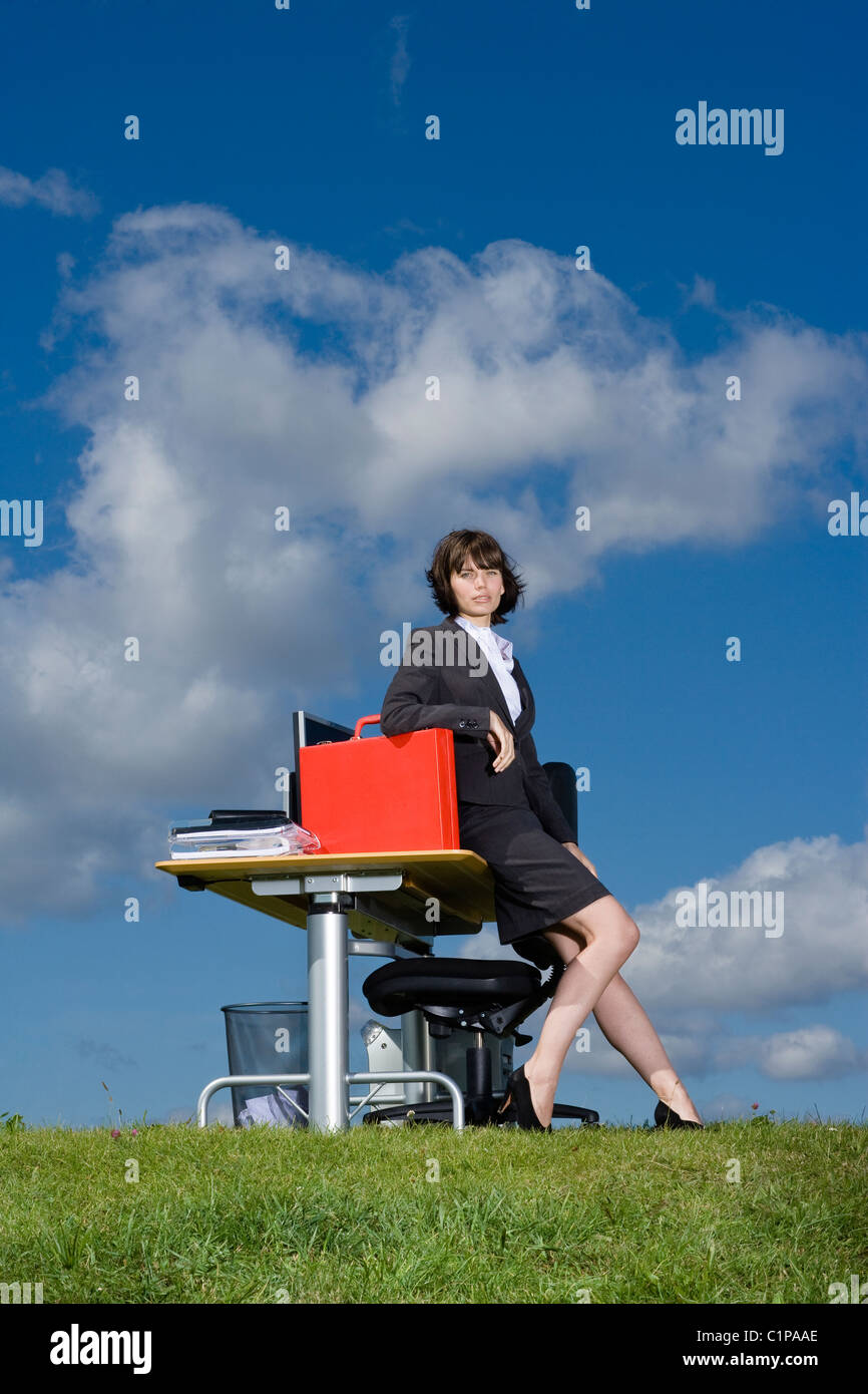 Businesswoman with red briefcase at desk in grass field Stock Photo Alamy