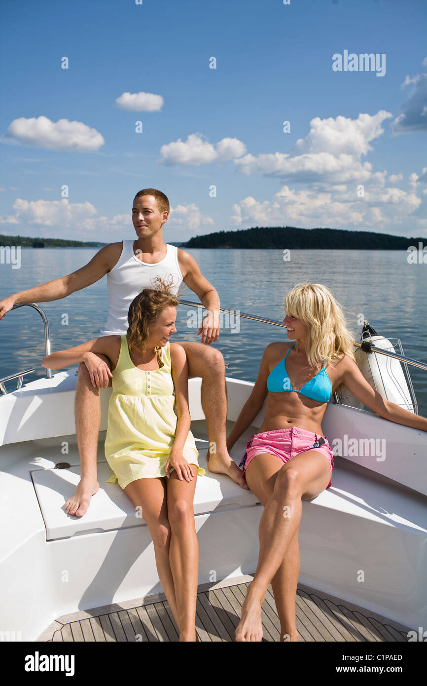 Two young women and young man sitting in yacht on lake Stock Photo