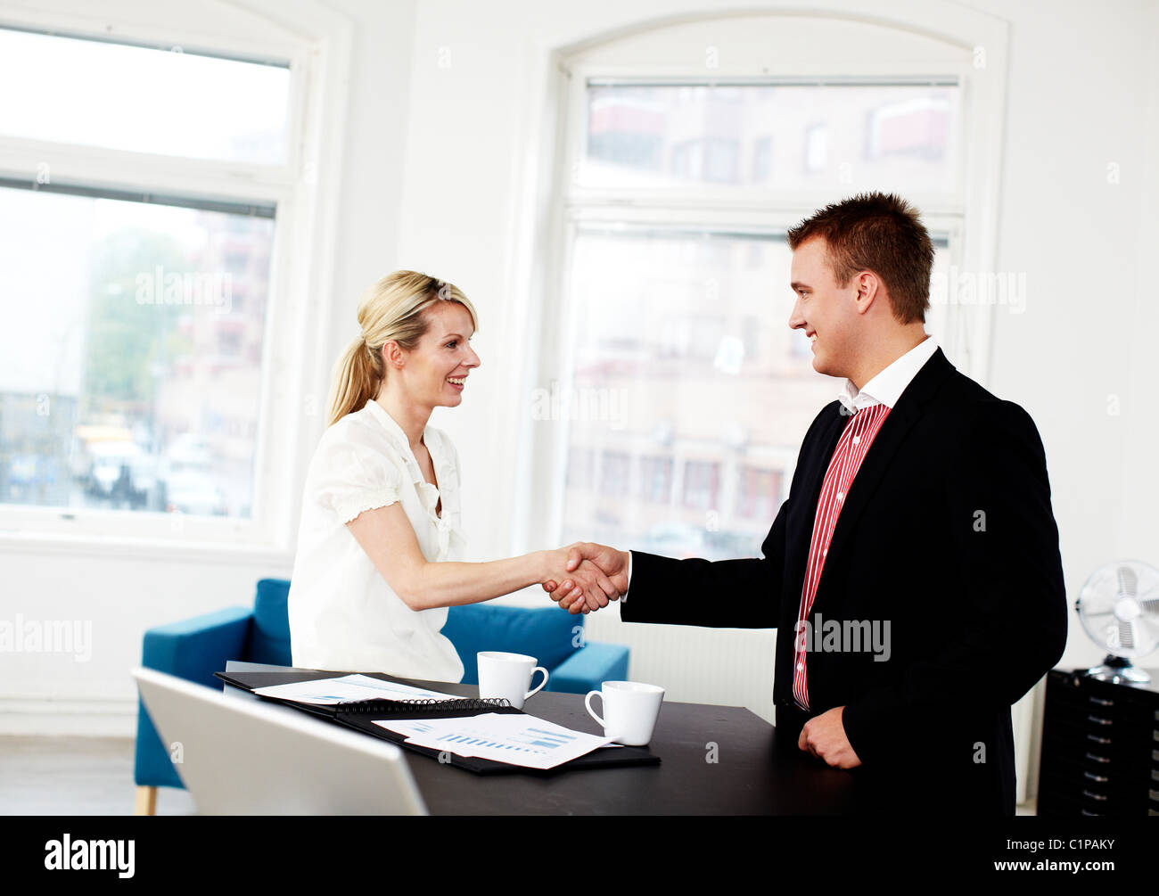 Businessman and woman shaking hands in office Stock Photo