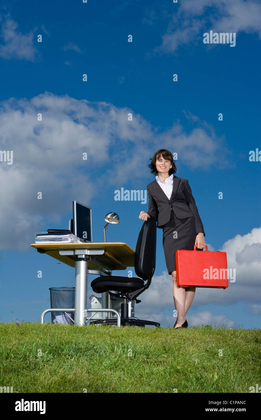 Businesswoman with red briefcase at desk in grass field Stock Photo Alamy