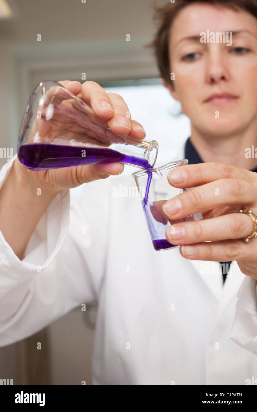 Scientist pouring liquid from beaker Stock Photo Alamy