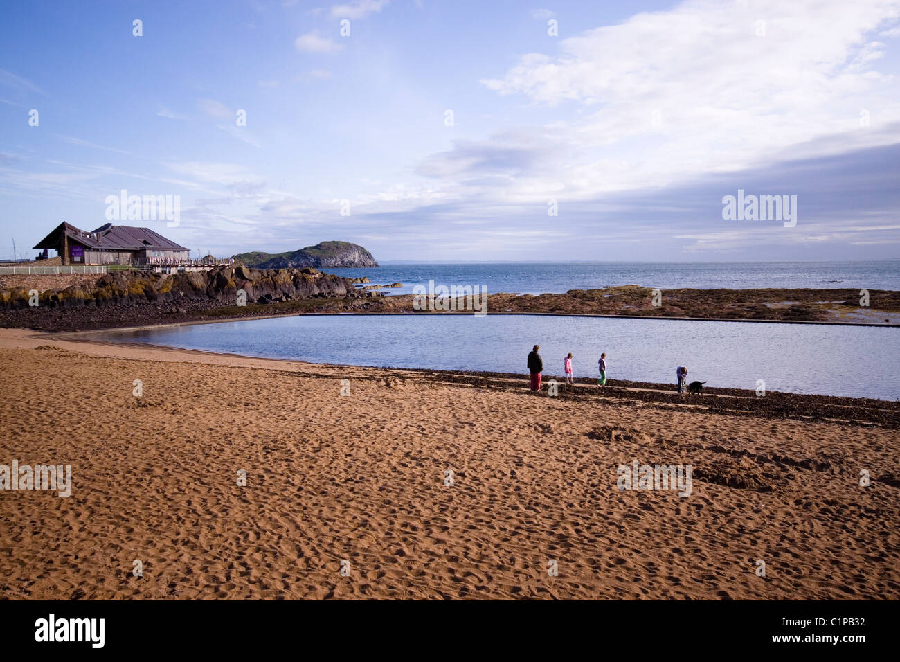 Scotland, North Berwick, Seabird Centre, people standing on beach at water's edge Stock Photo