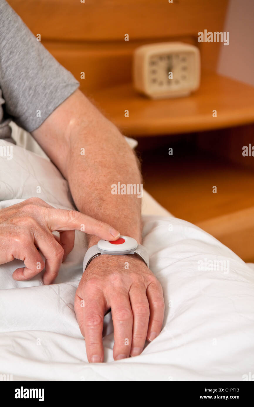 Senior Rufhilfe with emergency phone in bed Stock Photo