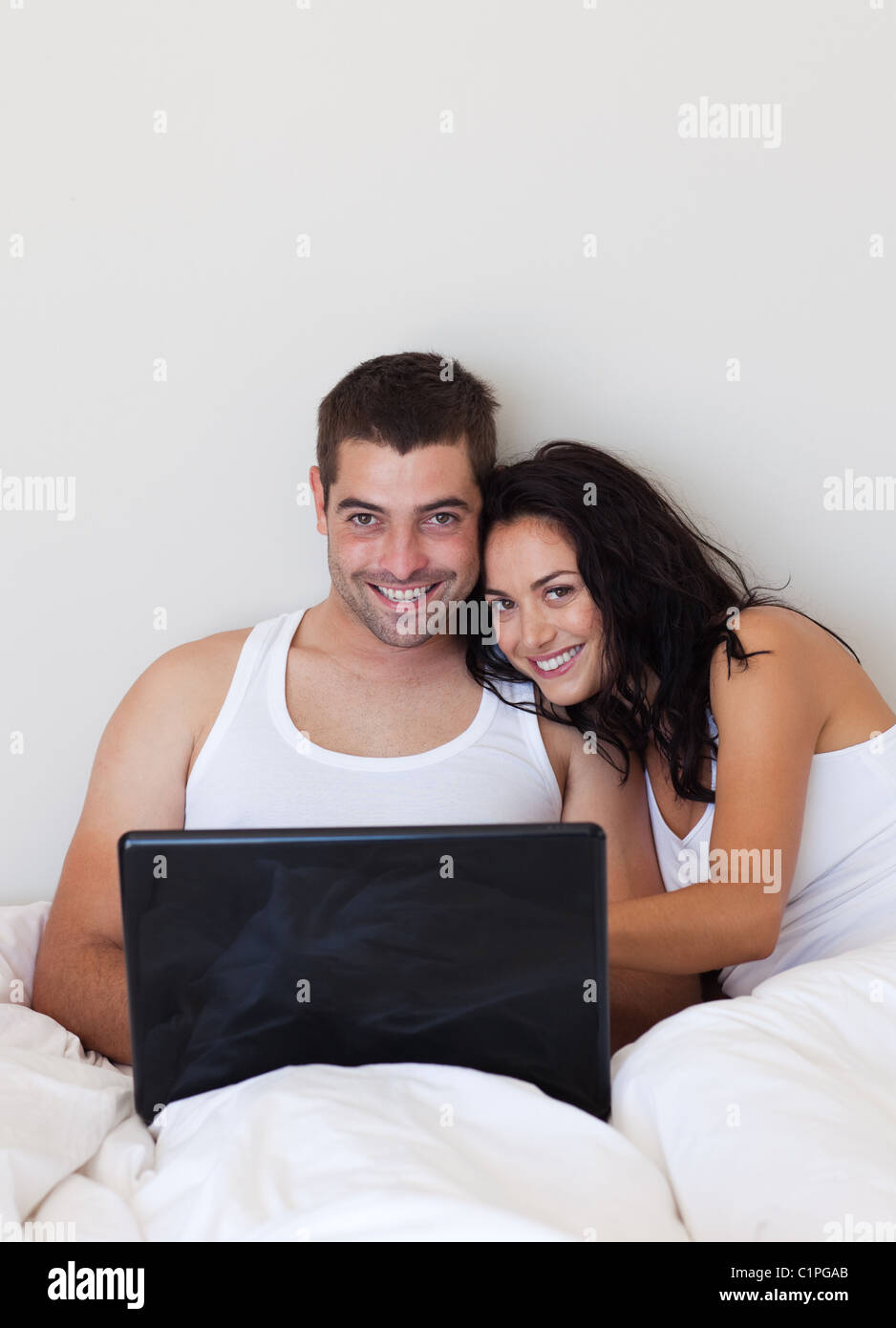 Smiling couple using a laptop lying in the bed Stock Photo - Alamy