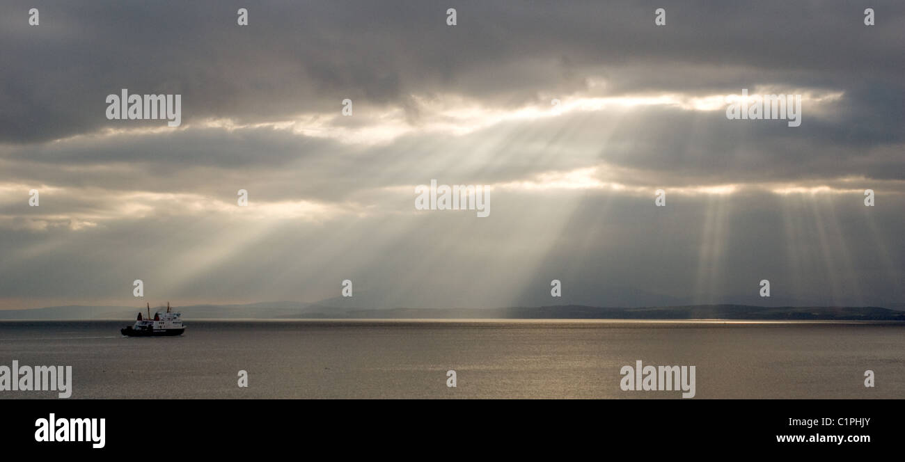 A ferry heads out from Wemyss Bay to Rothesay into crepuscular rays Stock Photo