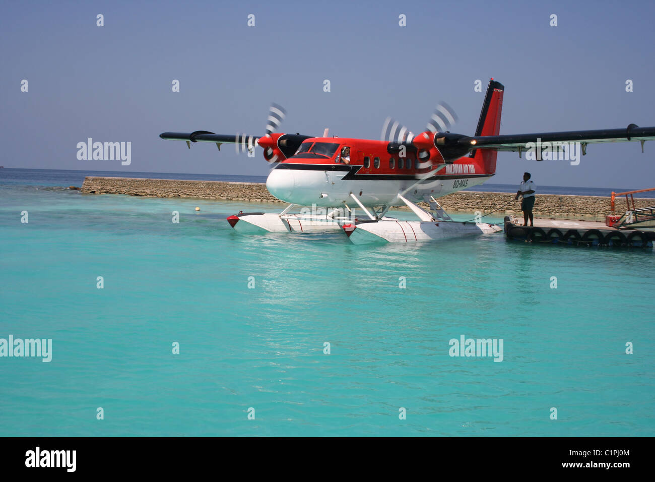 Sea plane sits in water by platform edge, Maldives, Indian Ocean. Stock Photo