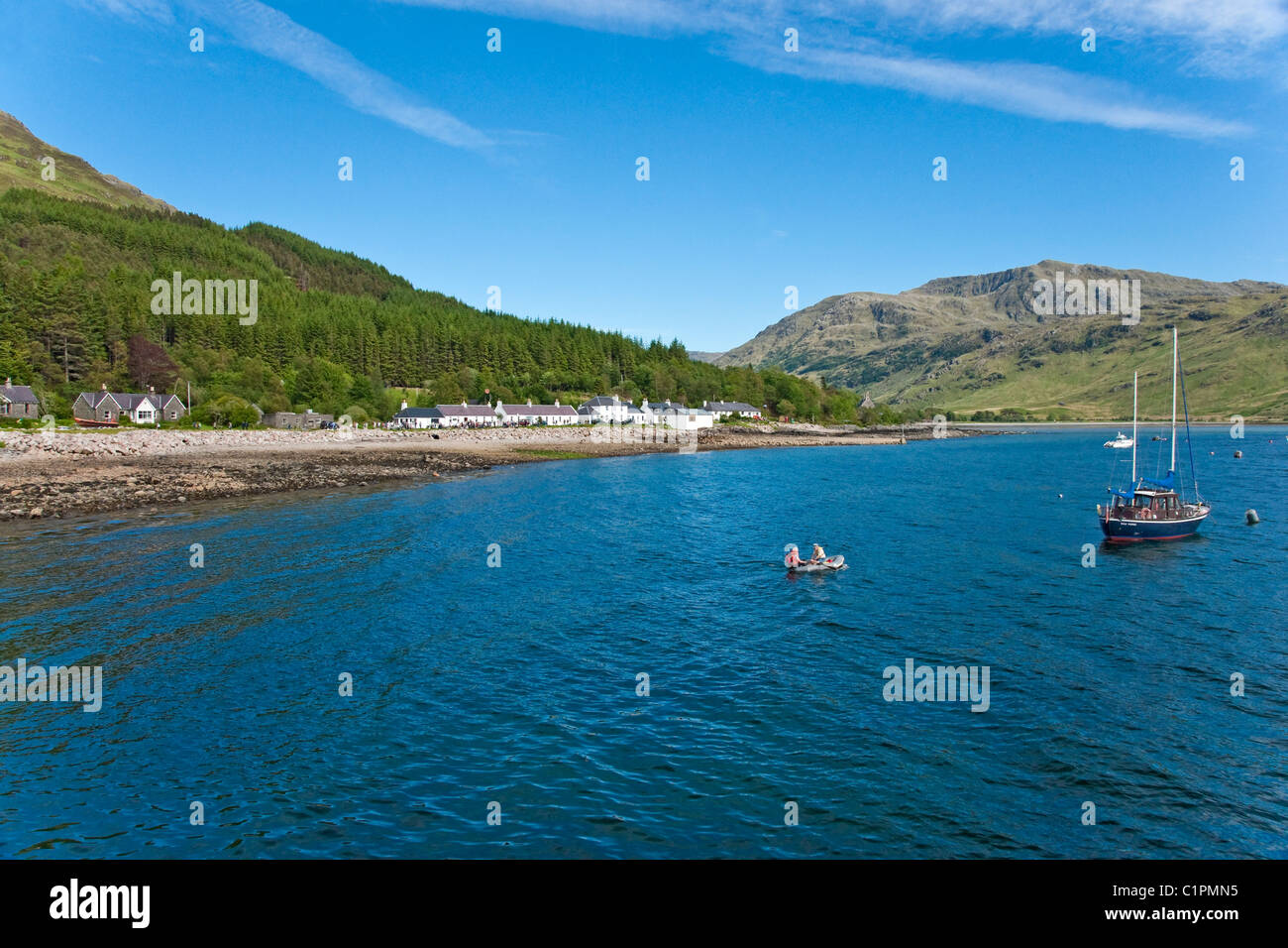 The small settlement of Inverie in Knoydart Highland of Scotland seen from Loch Nevis with sailors approaching their boat Stock Photo