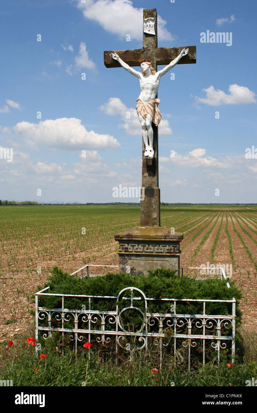 Alsace region, France. Statue of Jesus Christ on a stone cross stands in an empty field. Stock Photo