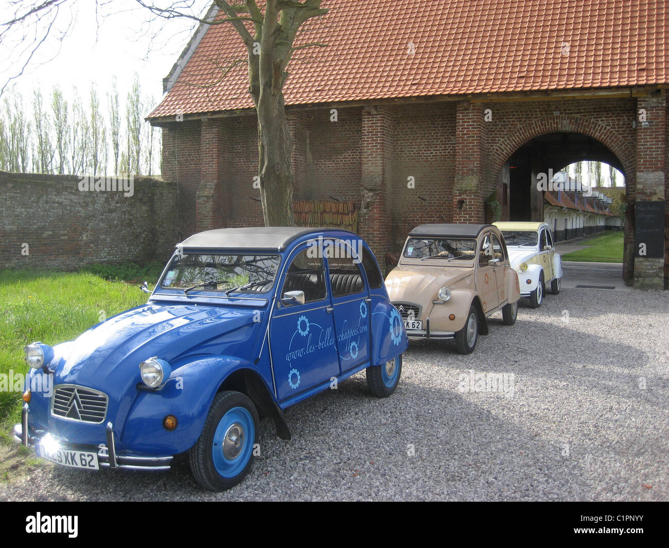 2008, Three different coloured 2CV cars lined up in a driveway, ready for hire or rental, Pas de