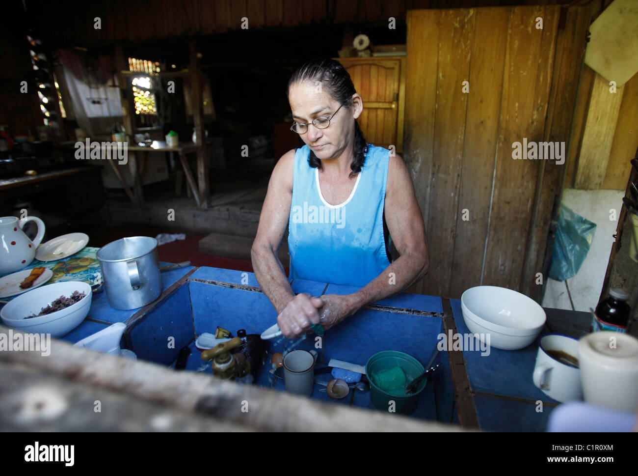 A Costa Rican woman washes dishes in her kitchen at home in the region of Volcan Tenorio, Costa Rica Stock Photo