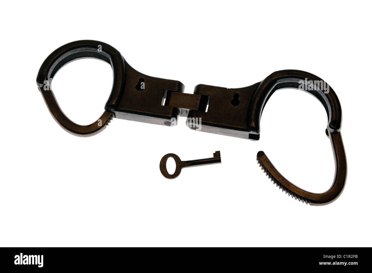 Handcuffs silhouetted against a plain background Stock Photo