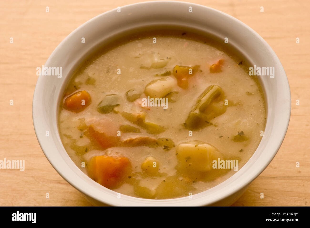 Vegetable soup in a ceramic white bowl on a wooden background. Stock Photo