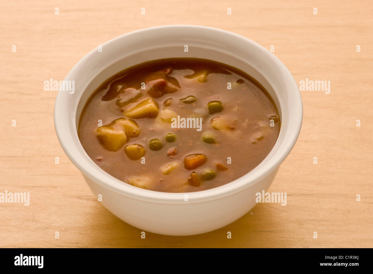 Vegetable soup in a ceramic white bowl on a wooden background. Stock Photo